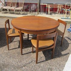 a wooden table and four chairs sitting on the ground next to each other in front of a building