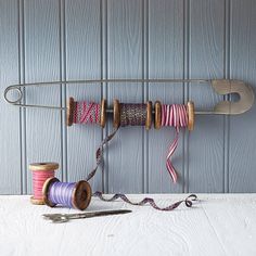 some spools of thread are hanging on a wall with a pair of scissors