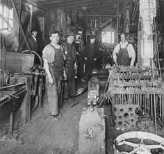 an old black and white photo of men working in a factory