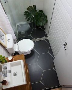 a small bathroom with black and white tile on the floor, shower stall, toilet and sink