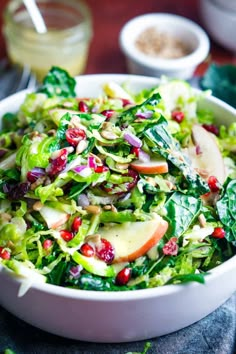 a white bowl filled with lettuce, apples and pomegranates