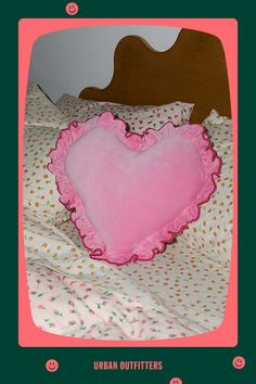 a pink heart shaped pillow sitting on top of a bed