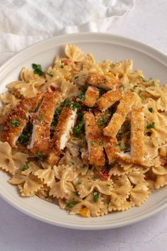 a white plate topped with pasta covered in sauce and chicken breast pieces on top of it