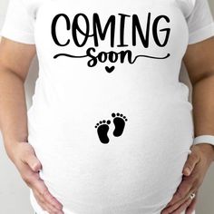 a pregnant woman wearing a white shirt that says coming soon