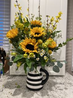 a black and white striped vase filled with sunflowers