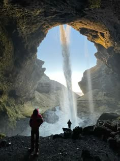 a person standing in front of a cave with water coming out from the entrance to it