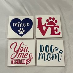 four coasters with different designs on them sitting on a bed together, one has a dog's paw and the other says rescue