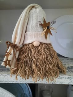 a close up of a stuffed animal with long hair and a hat on top of a shelf