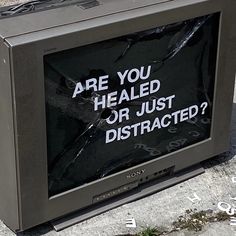 a tv sitting on the side of a road with a sign that says are you healed or just distracted?