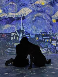 two people sitting on the ground in front of a starry night background with buildings