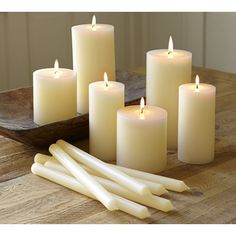 white candles are arranged on a wooden table