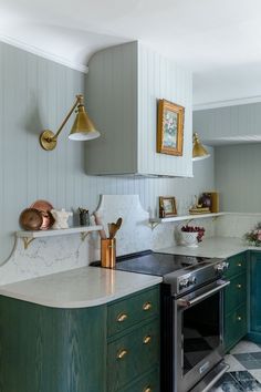 a kitchen with green cabinets and marble counter tops, gold accents on the hoods