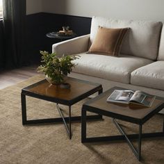 two coffee tables sitting on top of a carpeted floor next to a white couch