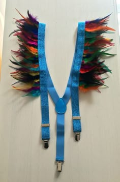 a blue strap with colorful feathers attached to it's ends on a white surface