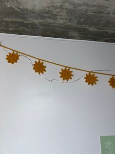 a string of crochet flowers is hanging from the ceiling in front of a white wall