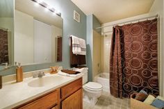 a bathroom with a toilet, sink and shower curtain in it's center area