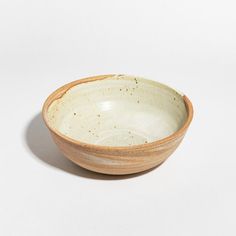 a white bowl with brown speckles sits on a plain surface, ready to be used as a serving dish