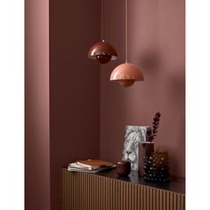 two pendant lights hanging from the ceiling in a room with pink walls and wood paneling