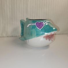 a ceramic teapot with a purple heart on it