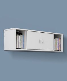 a white wall mounted entertainment center with dvd's on the doors and shelves above it