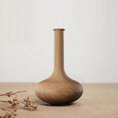 a wooden vase sitting on top of a table next to dried flowers