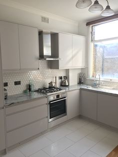 a kitchen with all white cabinets and stainless steel appliances