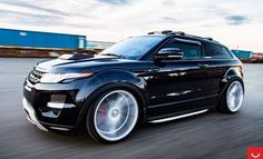 a black land rover driving down the road with its wheels on it's tires