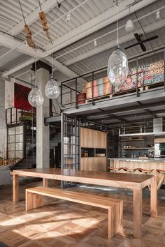 a large wooden table sitting in the middle of a room next to a metal staircase