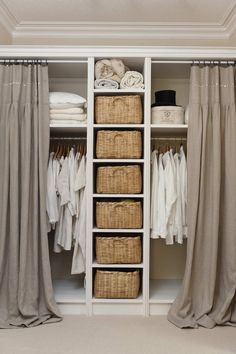 an open closet with clothes and linens in baskets on the bottom shelf next to curtains