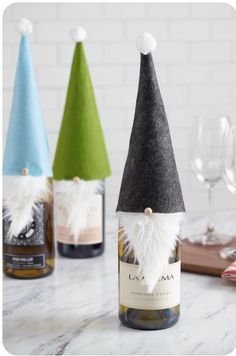 three wine bottles with gnome hats on them sitting on a table next to some glasses