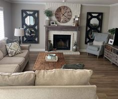 a living room filled with furniture and a clock on the wall above it's fireplace