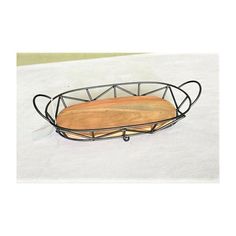 a wooden cutting board in a metal basket on a white tablecloth covered surface,