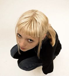 a woman with blonde hair is looking up at the camera while wearing black shirt and jeans