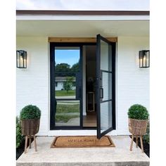 the front door to a white house with two planters on either side of it