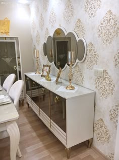 a white table topped with two sinks and mirrors next to a wallpapered wall