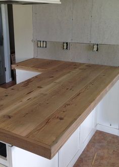 a kitchen counter made out of wood in the middle of a room with white cabinets