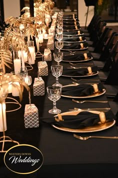 a long table is set up with black and gold place settings, candles and napkins