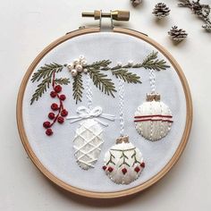 an embroidered christmas ornament with pine cones and baubles