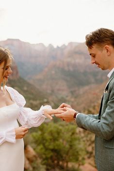 a bride and groom exchanging wedding rings in the mountains