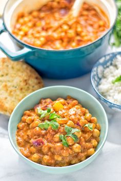 a bowl of chickpeas and rice next to two bowls of pita bread