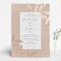 a wedding card with leaves on it next to a vase