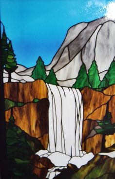 a stained glass window with a waterfall and trees