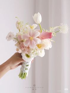 a person holding a bouquet of flowers in their hand with white and pink petals on it