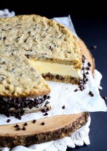 a chocolate chip cheesecake cut in half on top of a wooden cutting board with one slice taken out