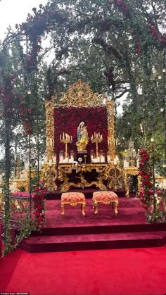 the altar is decorated with red flowers and greenery, along with gold benches for seating