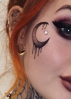 a woman with red hair and makeup has her face painted to look like a crescent moon