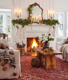 a living room filled with furniture and a fire place in front of a mantle covered in greenery