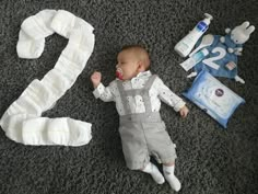 a baby is laying on the floor next to some diapers and other items for his first birthday