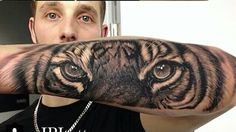 a man with a tiger tattoo on his arm and hand is looking at the camera