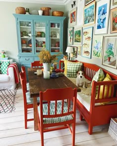 a dog sitting on a bench in front of a table with chairs and pictures on the wall